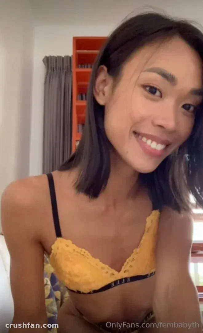 Femby smiling in a yellow bra in a bright indoor selfie
