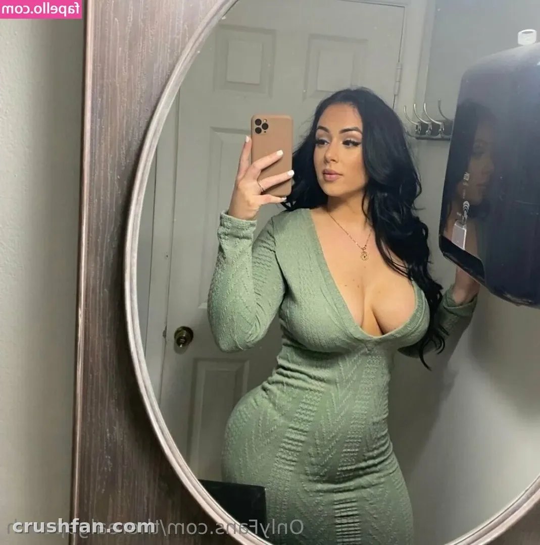 Hayley Davis in a sage green long-sleeved dress taking a mirror selfie indoors