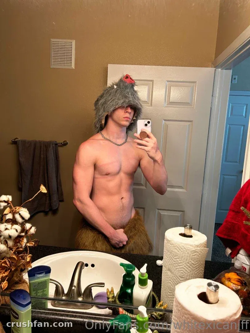 Creator in a furry hat and costume taking a mirror selfie in a bathroom.
