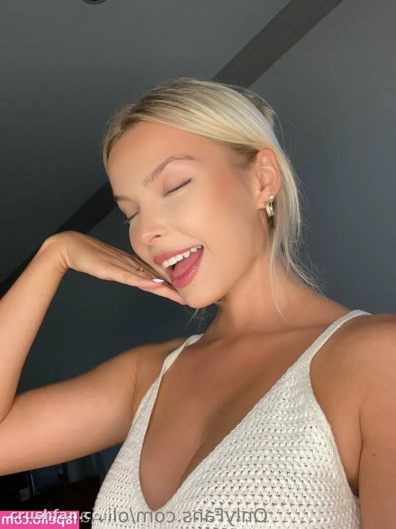 Blonde woman in a white crochet top smiling with eyes closed in a close-up selfie