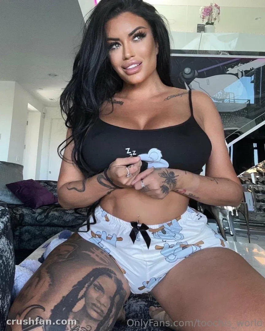 Toochi Kash seated indoors in a black crop top and printed shorts