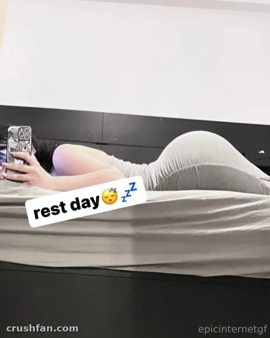 Anna allongée sur un lit dans une tenue gris clair tenant un téléphone
