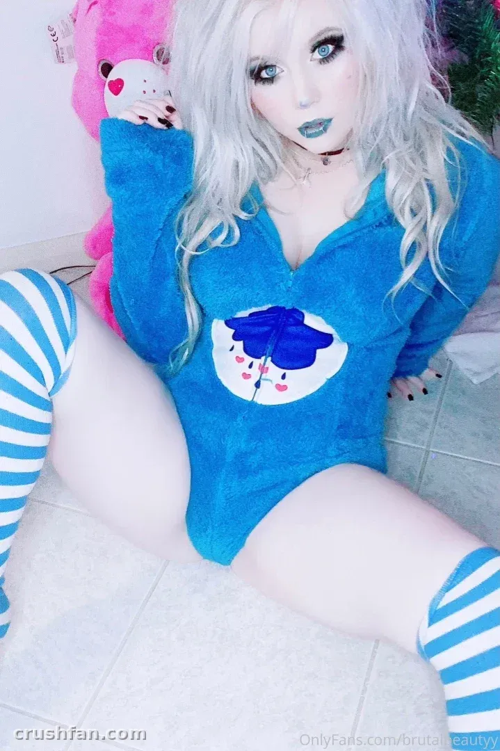 Criadora em um macacão azul e meias listradas sentada em um piso de ladrilhos ao lado de um bichinho de pelúcia rosa