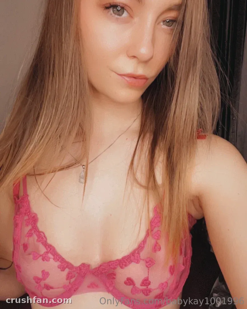 Babykay se toma una selfie en primer plano con un sujetador de encaje rosa y un collar con colgante.