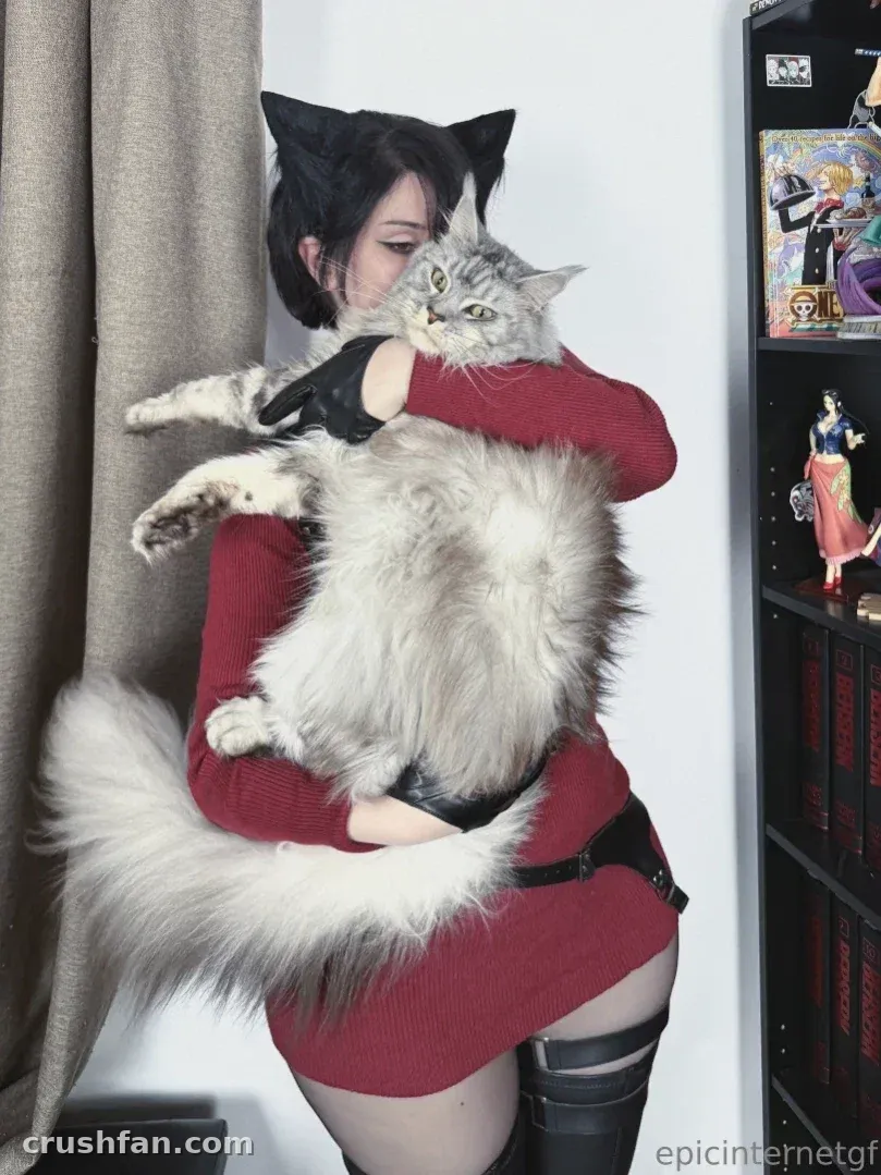 Anna in a red dress holding a large fluffy cat indoors
