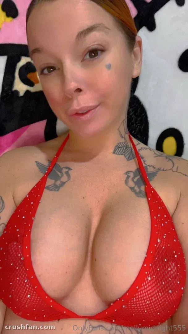 Selfie de perto de Molly midnight em um top halter vermelho brilhante contra um fundo estampado em rosa e preto
