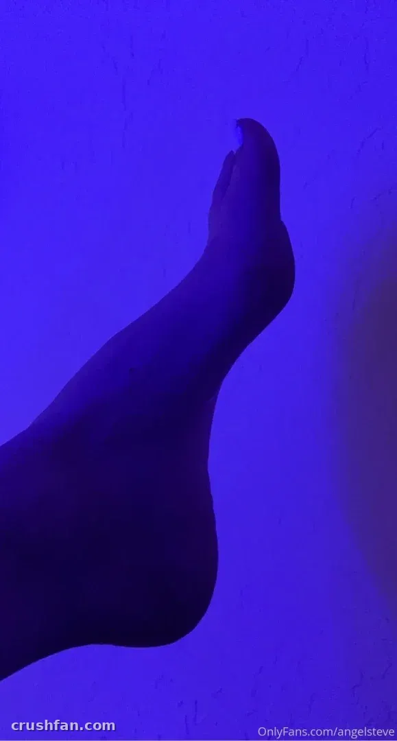Silhouette eines erhobenen Fußes vor einer tiefblau beleuchteten Wand