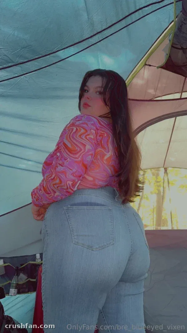 Miss Bunny in a patterned top and jeans inside a tent, looking over her shoulder