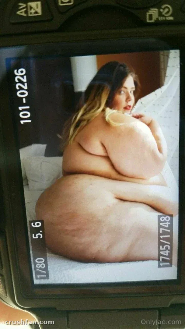 Jae Moonbeam assise sur une surface blanche, vue à travers l'écran d'un appareil photo numérique.