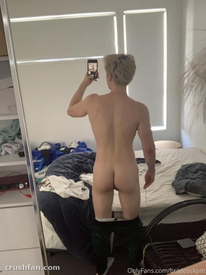 Brad Cockpitt prenant un selfie miroir dans une chambre avec un lit et des étagères blanches.