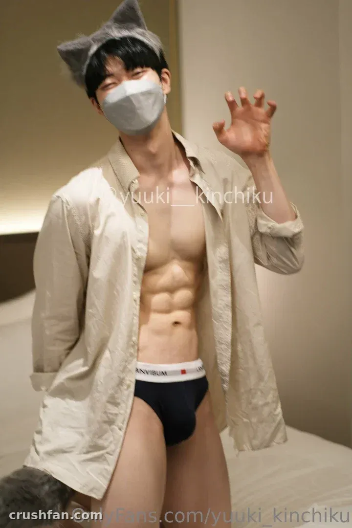 Yuuki in a cat ear headband, face mask, and open beige shirt posing indoors.