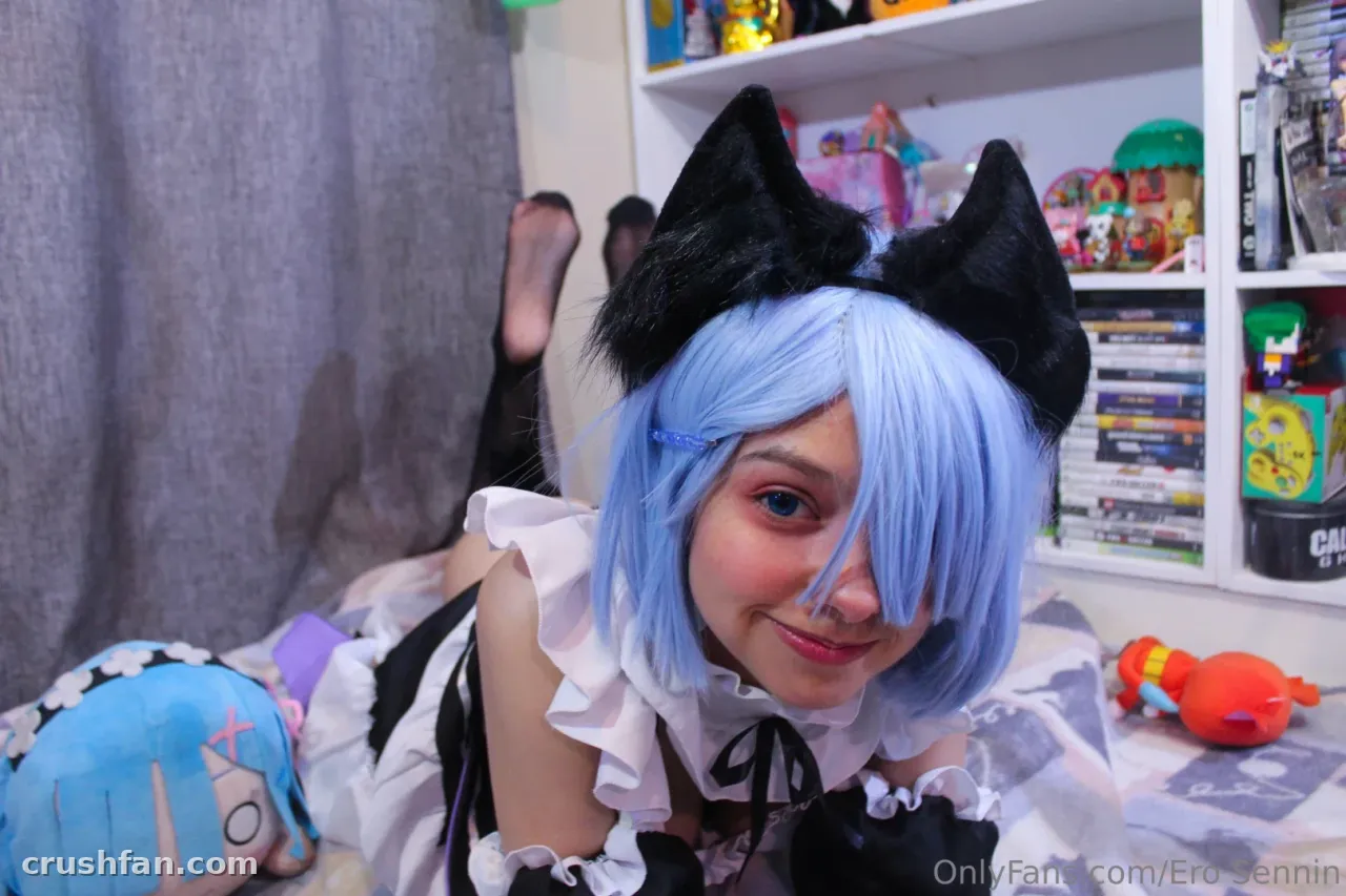 Cosplayer de peruca azul e orelhas de gato pretas deitada em uma cama com um traje estilo empregada