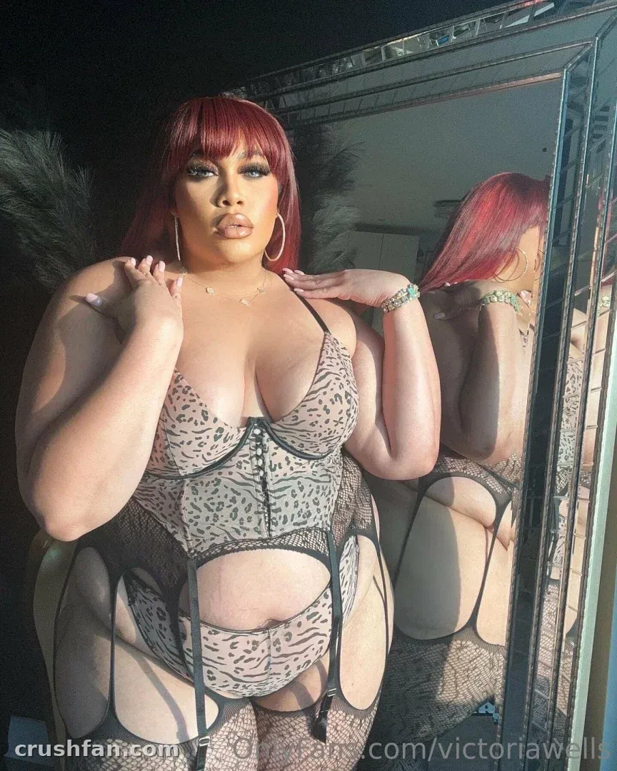 Victoria Wells posing in leopard print lingerie in front of a framed mirror