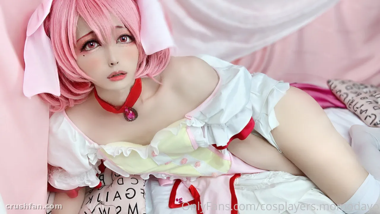 Creator in a pink wig and ruffled white costume reclining against pink fabric
