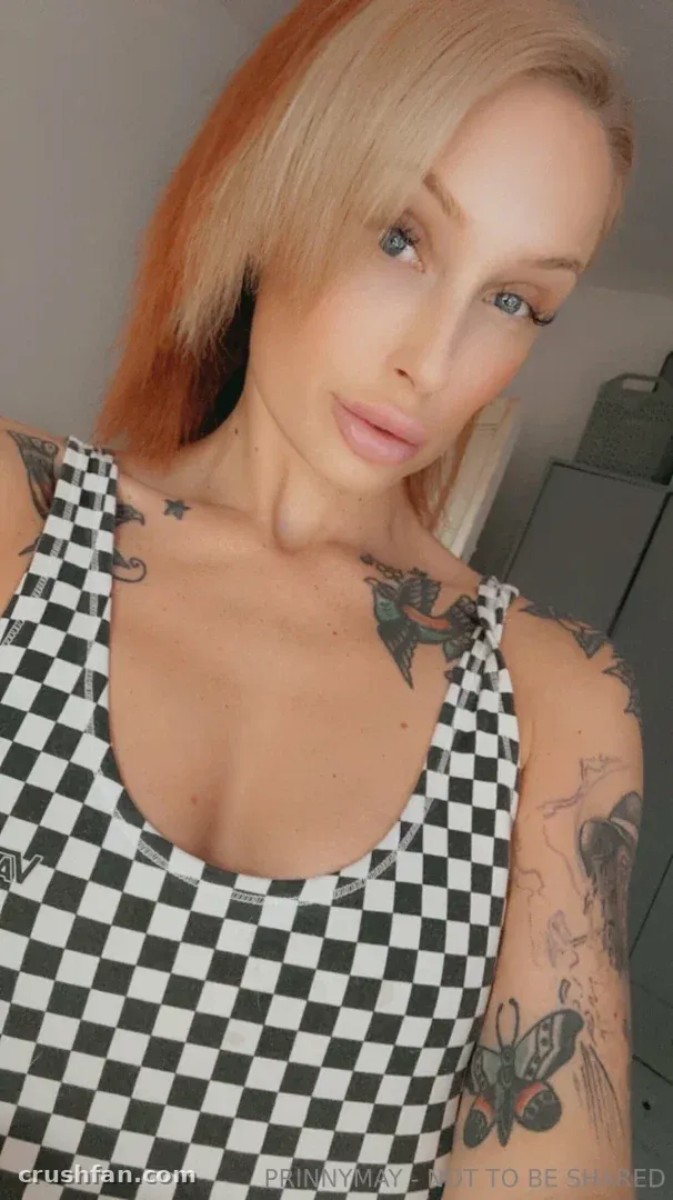 Prinny May prenant un selfie en gros plan dans un débardeur à carreaux noir et blanc en intérieur.