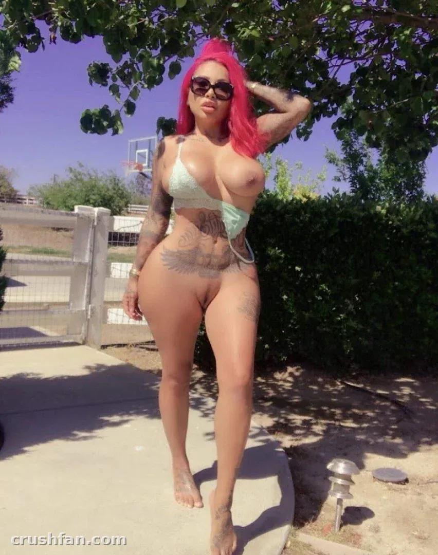 Brittanya in einem mintgrünen Bikini und Sonnenbrille, die an einem sonnigen Tag im Freien steht.