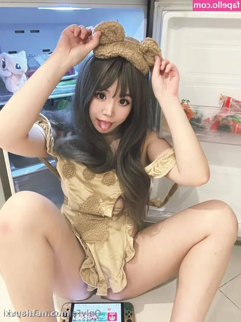 Yuki crouching by an open fridge in a beige teddy-pattern outfit and fuzzy headband