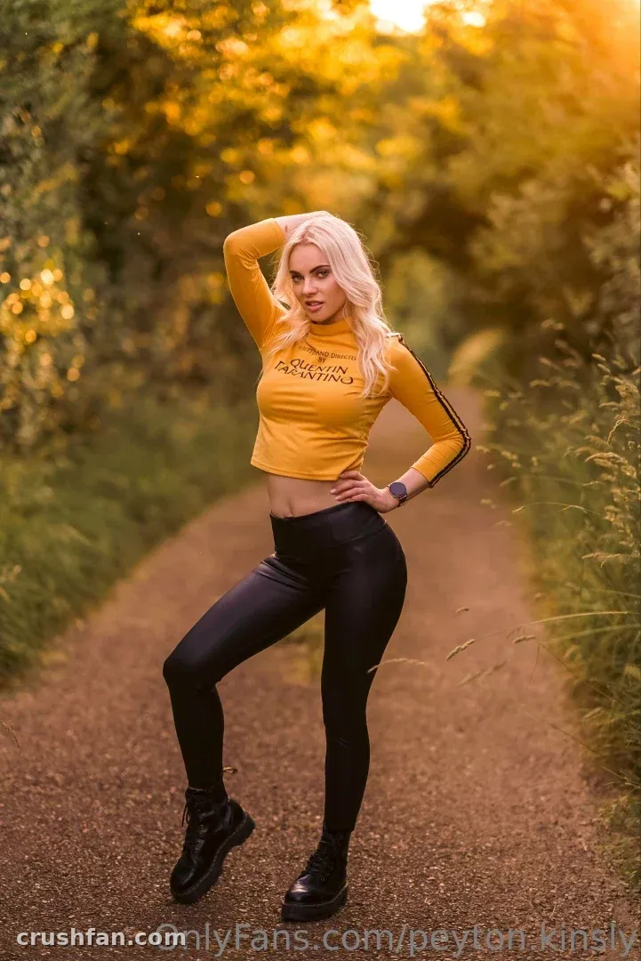 Peyton com um top cropped amarelo e leggings pretas em uma estrada de terra ensolarada