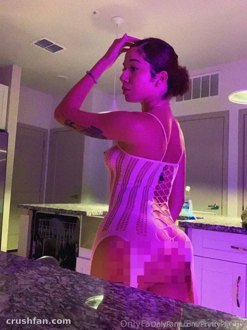 Prettypinklily in a camisole standing in a kitchen lit by pink light