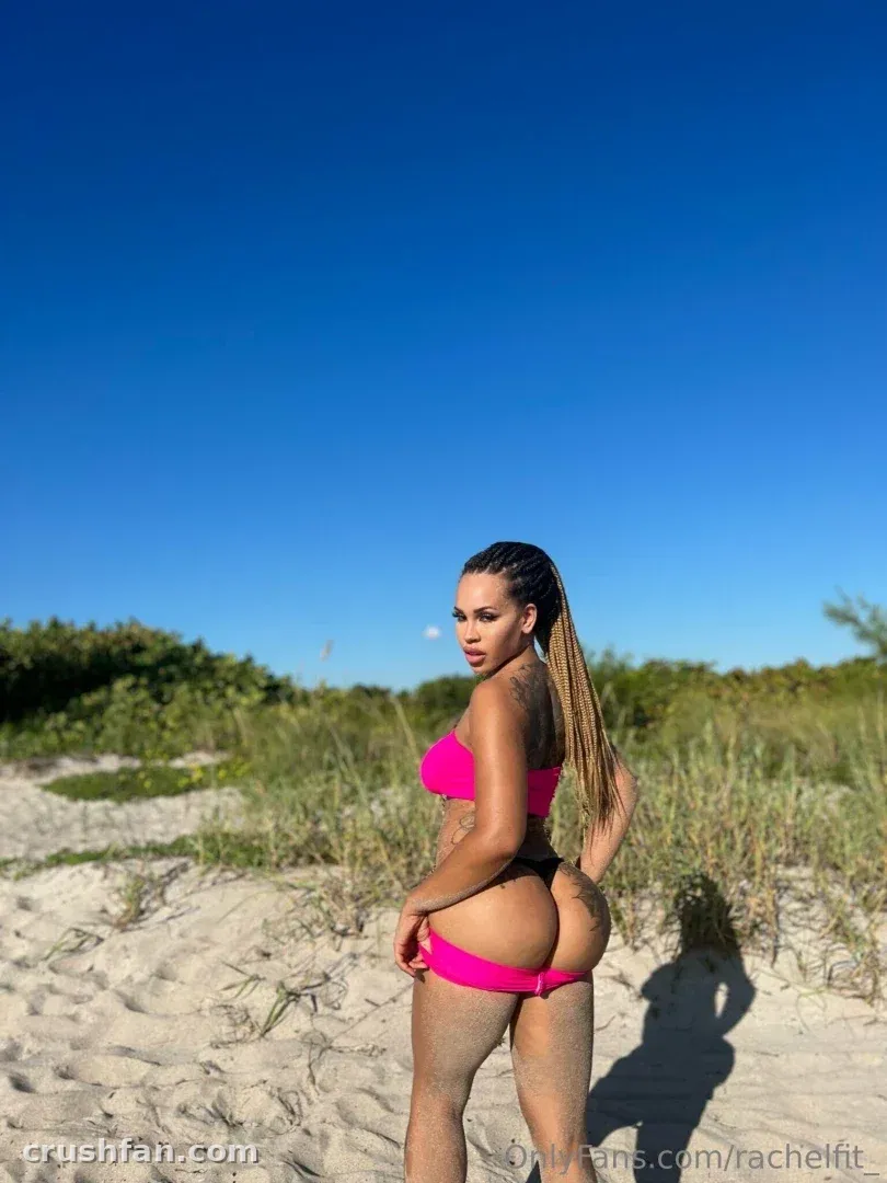 Rachel in a pink two-piece standing on sandy dunes under a clear blue sky