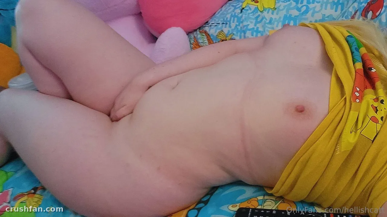 Creator lying on colourful cartoon-print bedding wearing a lifted yellow top