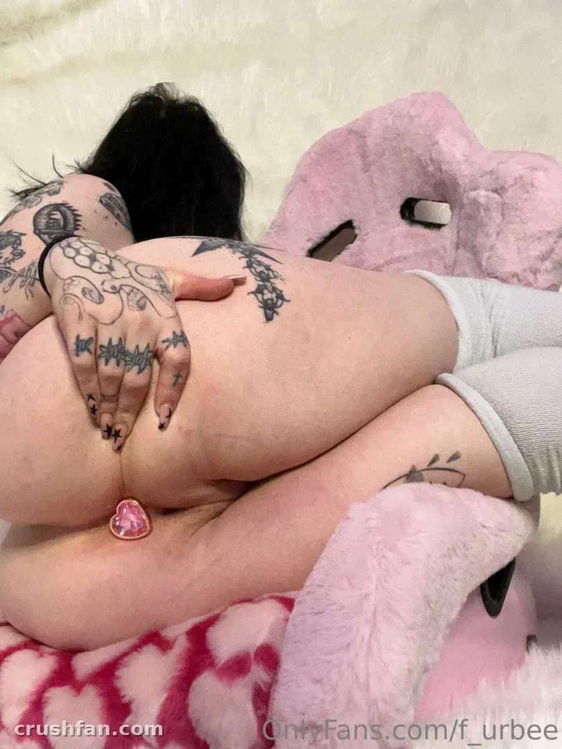 Criadora tatuada relaxando sobre roupa de cama rosa felpuda com meias cinza-claras
