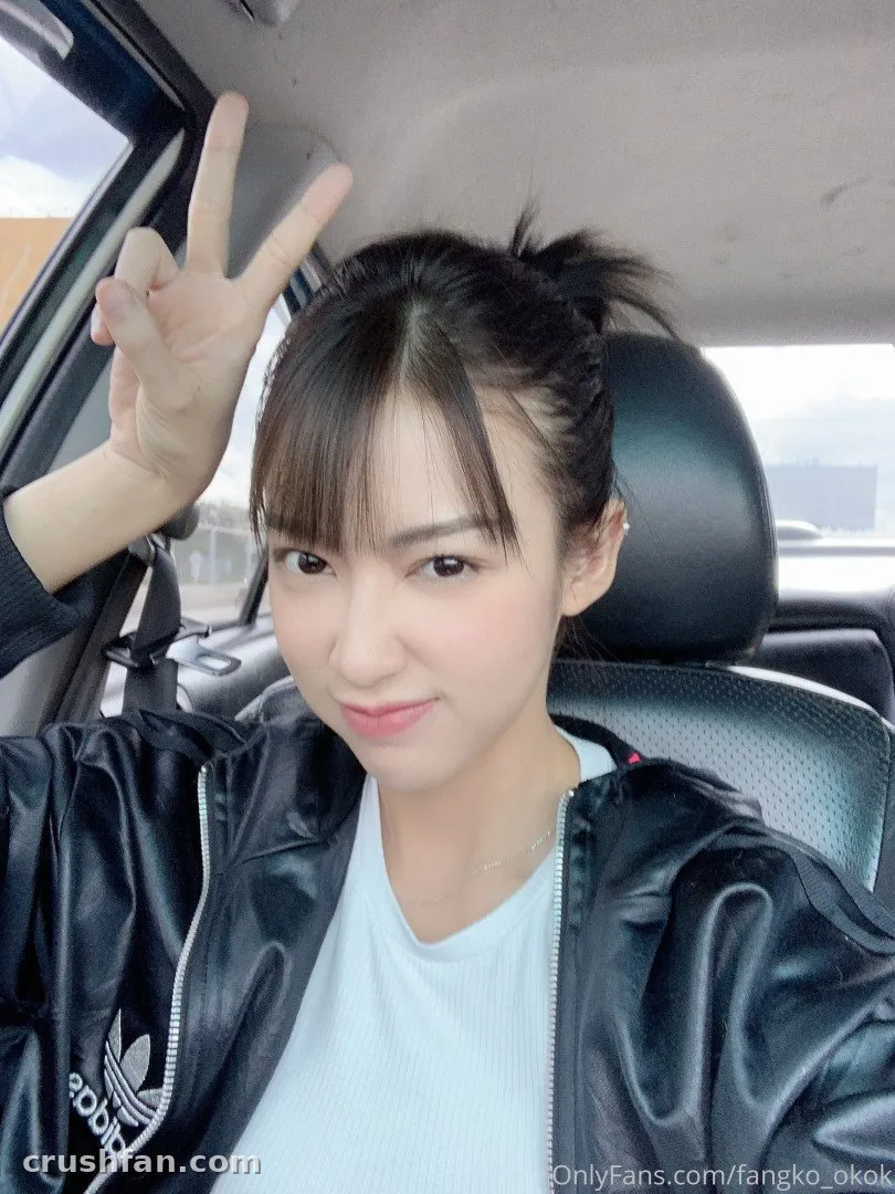 Fangko in a car making a peace sign while wearing a black jacket.