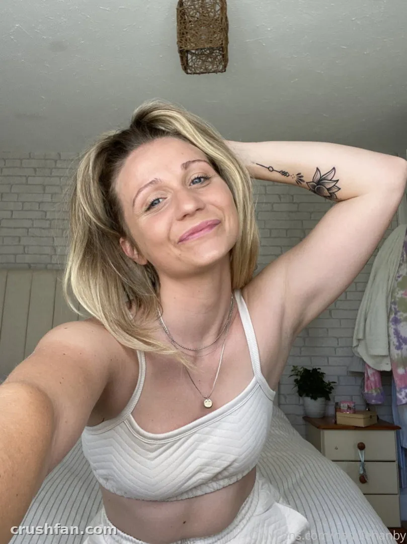 Natalie Hanby in einem weißen Crop-Top lächelnd in einem hellen Schlafzimmer-Selfie.