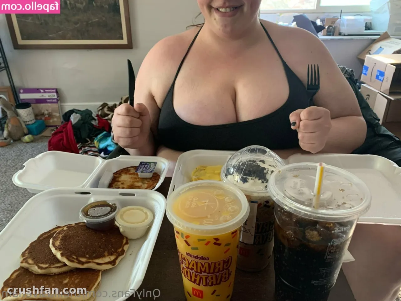 Sabrina in a black halter top seated behind a takeaway breakfast with pancakes and iced drinks