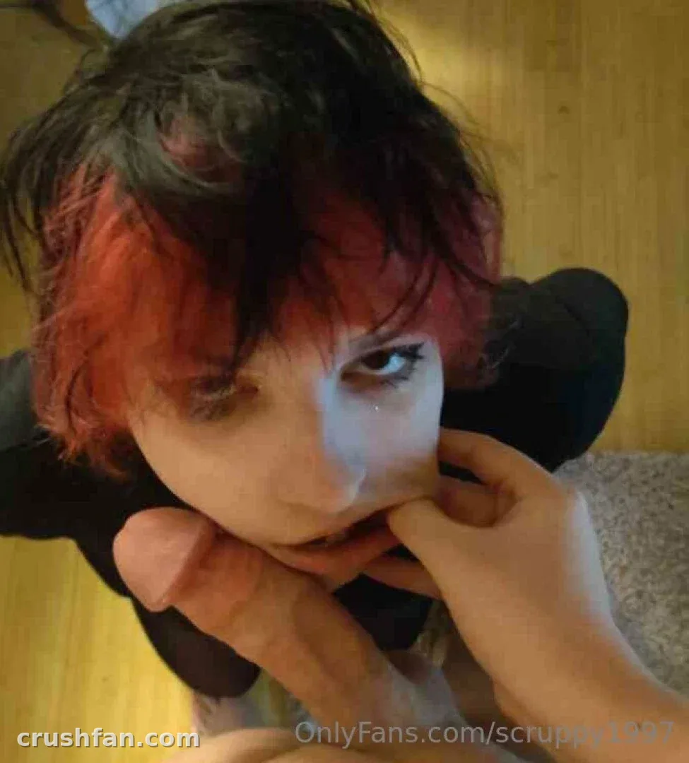 Portrait en gros plan en intérieur d'une personne aux cheveux foncés avec des mèches rouges regardant l'objectif