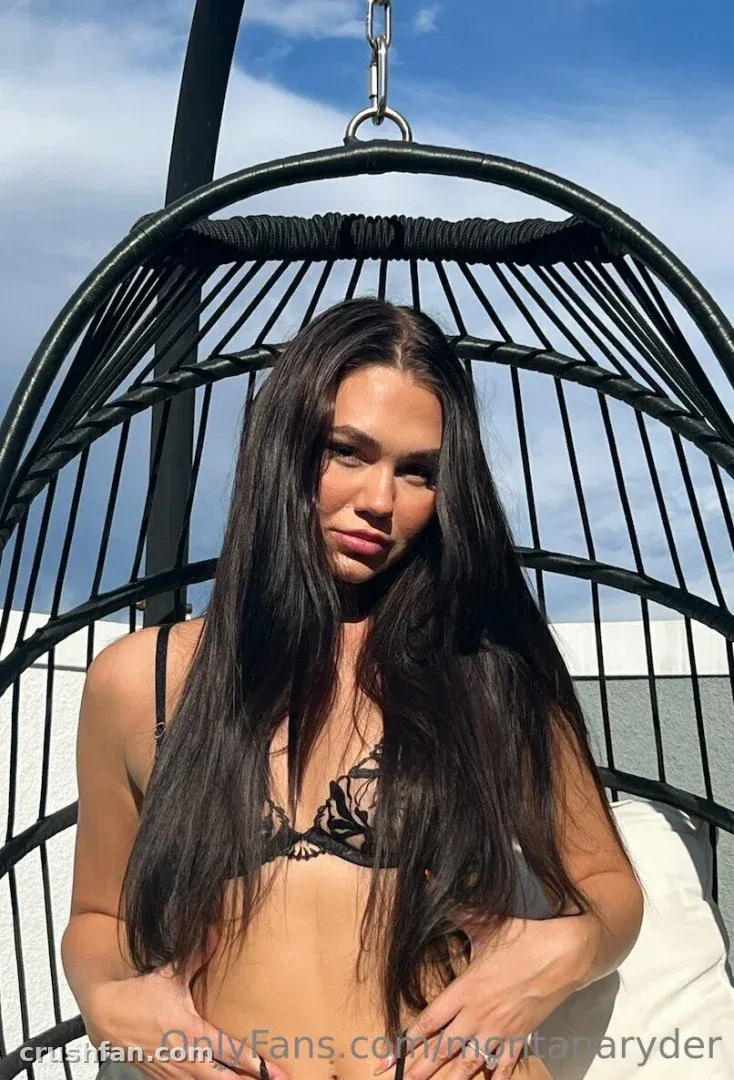 Montana Ryder sentada em uma cadeira ovo preta contra um céu azul