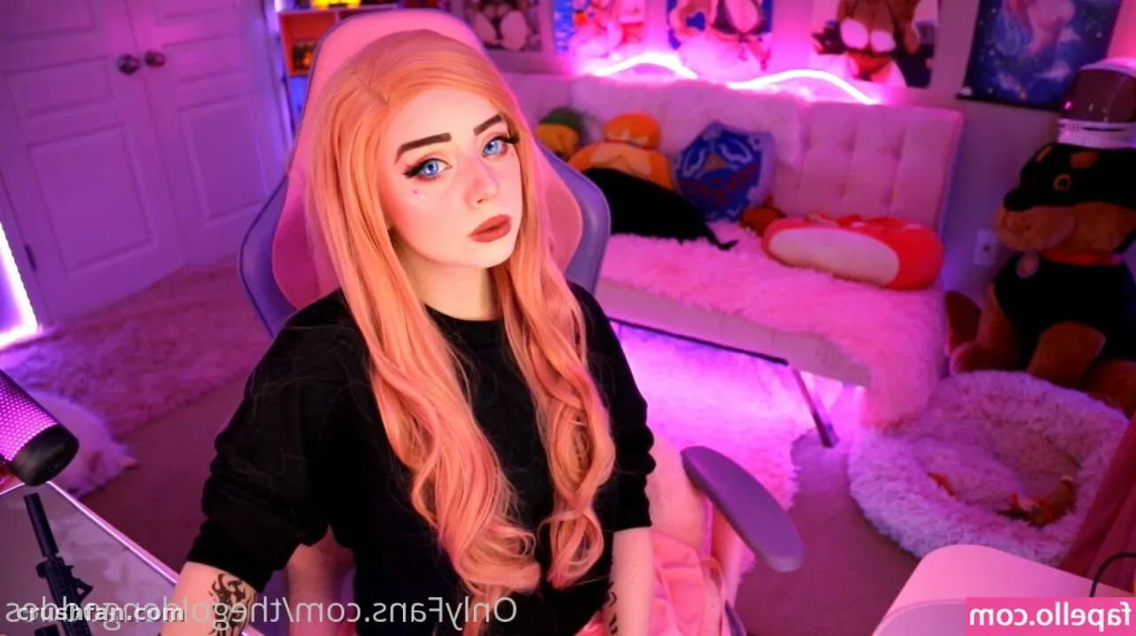 Sammy en haut noir assise dans une salle de gaming éclairée en rose avec des peluches derrière elle