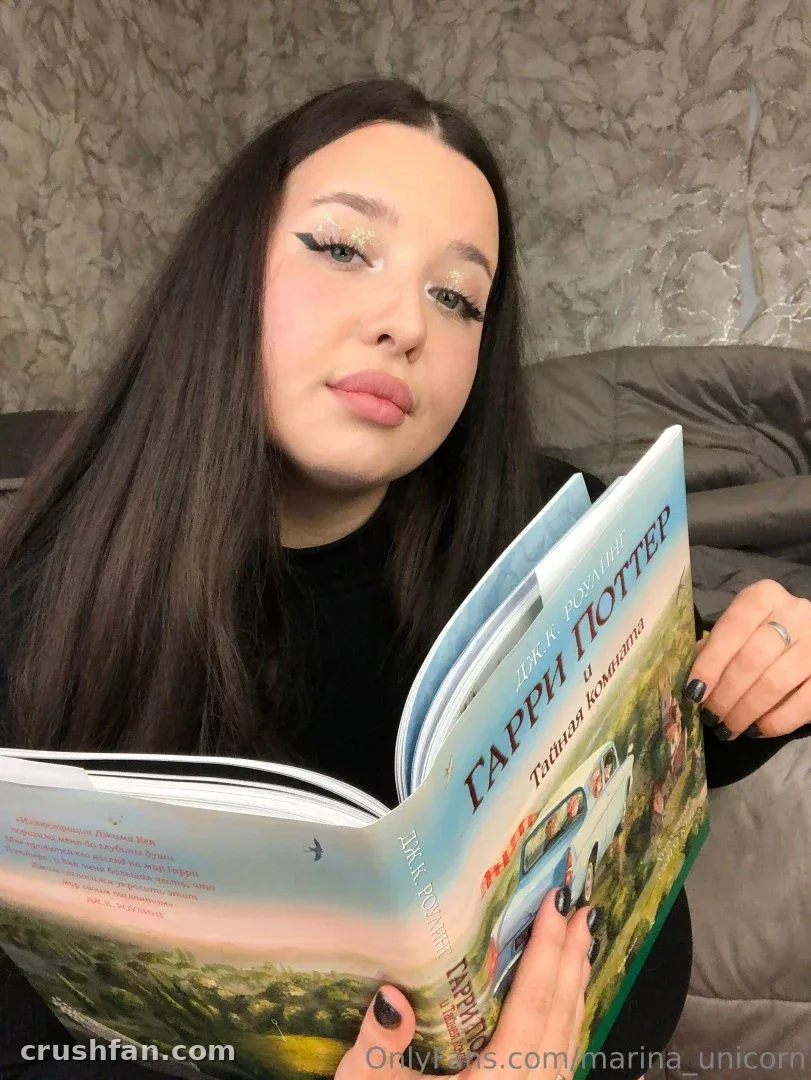 Marinetta in a black top holding an open illustrated book indoors