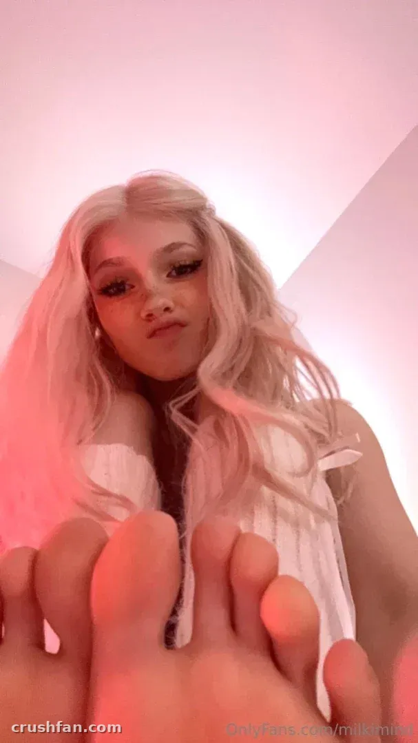 Milki with long blonde hair in pink light, bare feet toward the camera