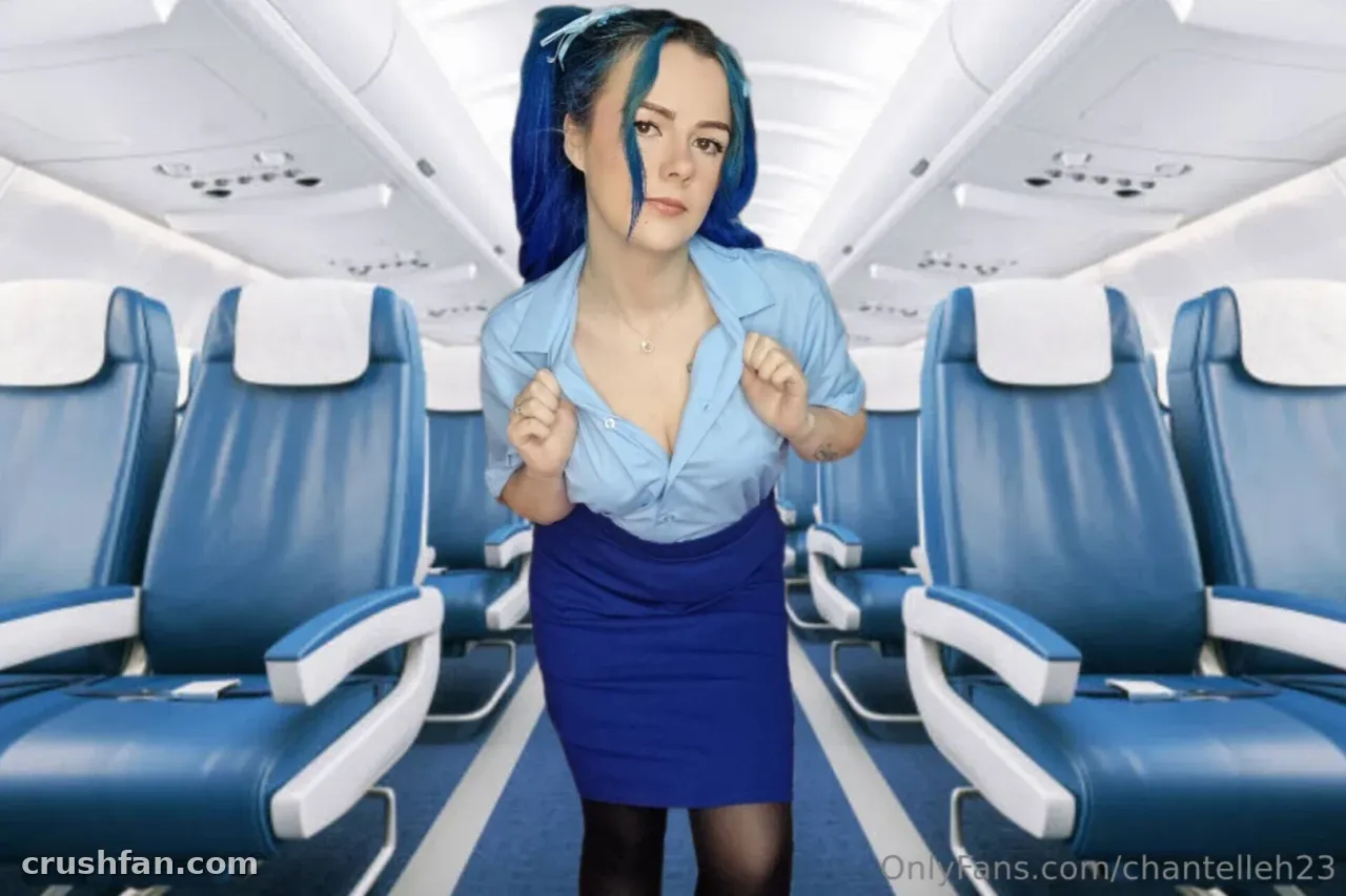 Femme en tenue bleue d'hôtesse de l'air debout dans le couloir d'une cabine d'avion.