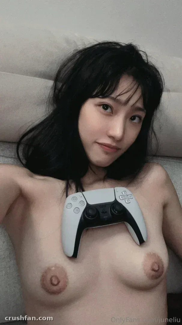 June Liu SpicyGum sosteniendo un mando de videojuegos blanco contra un fondo interior neutro