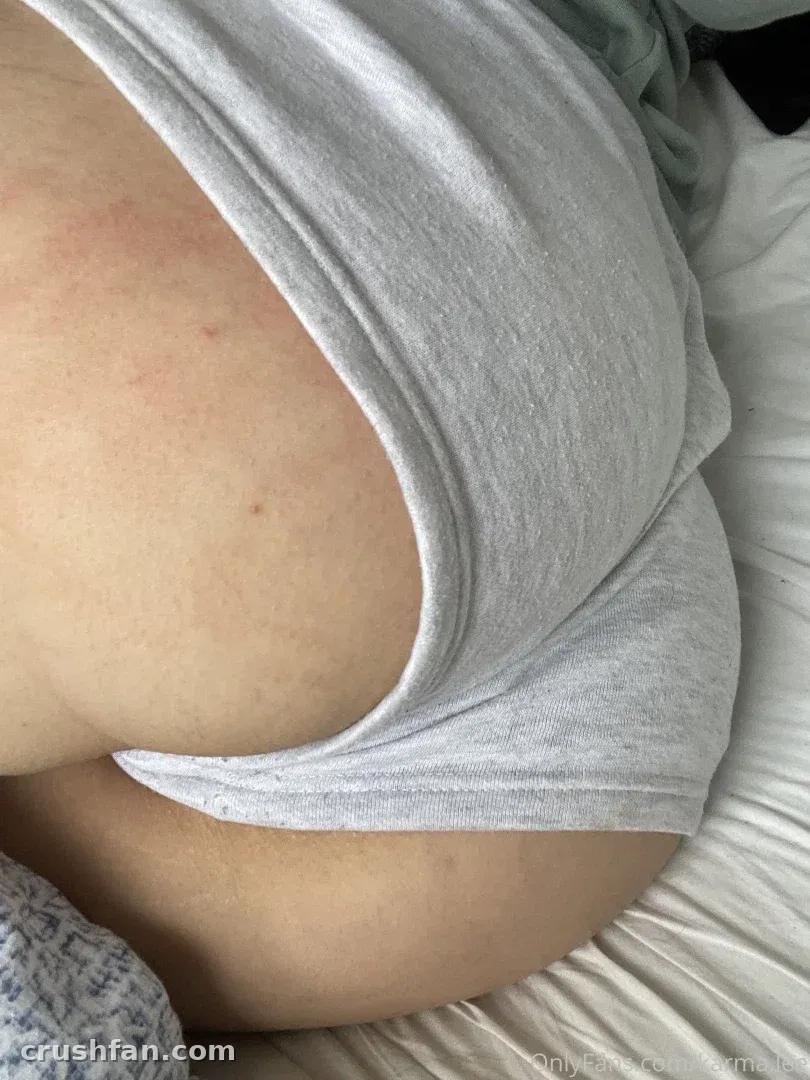 Close-up of soft grey loungewear fabric against skin on pale bedsheets