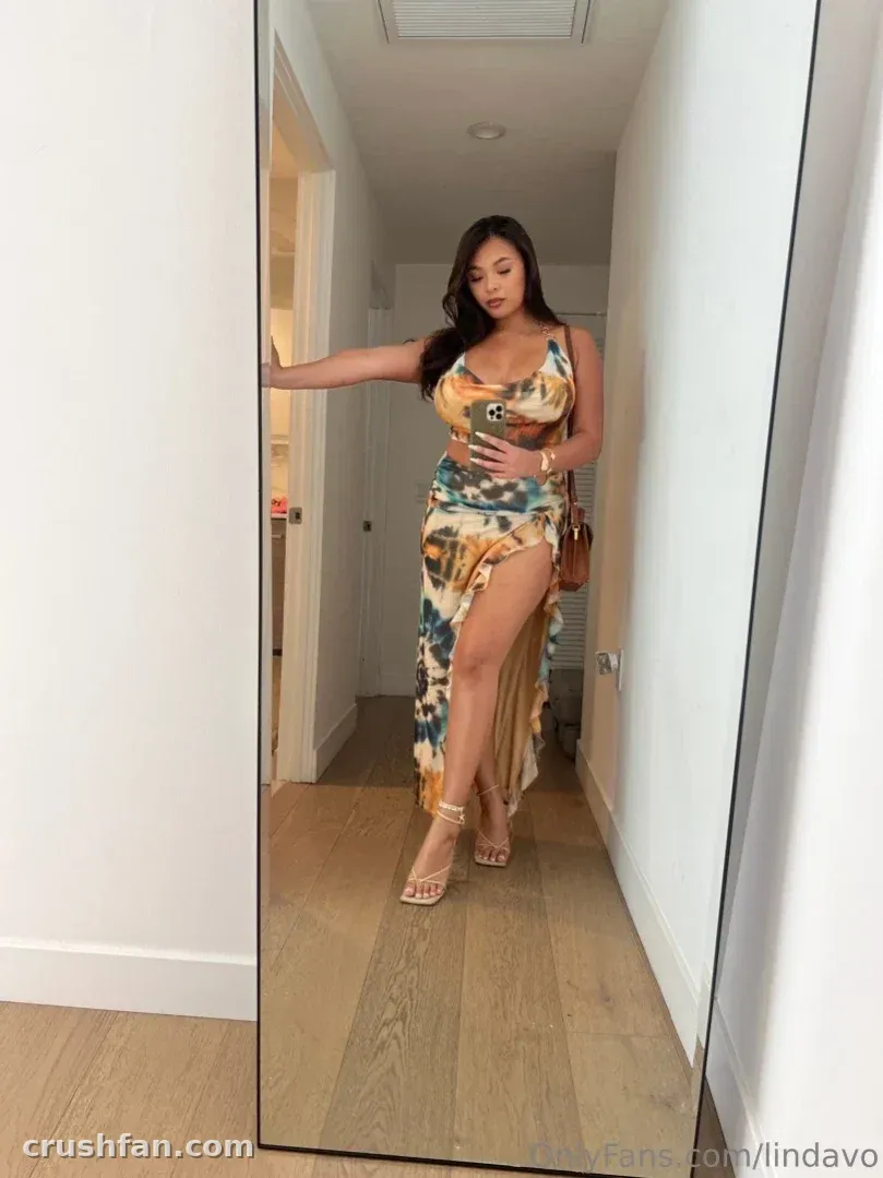 Linda Vo in a patterned dress taking a mirror photo in a hallway