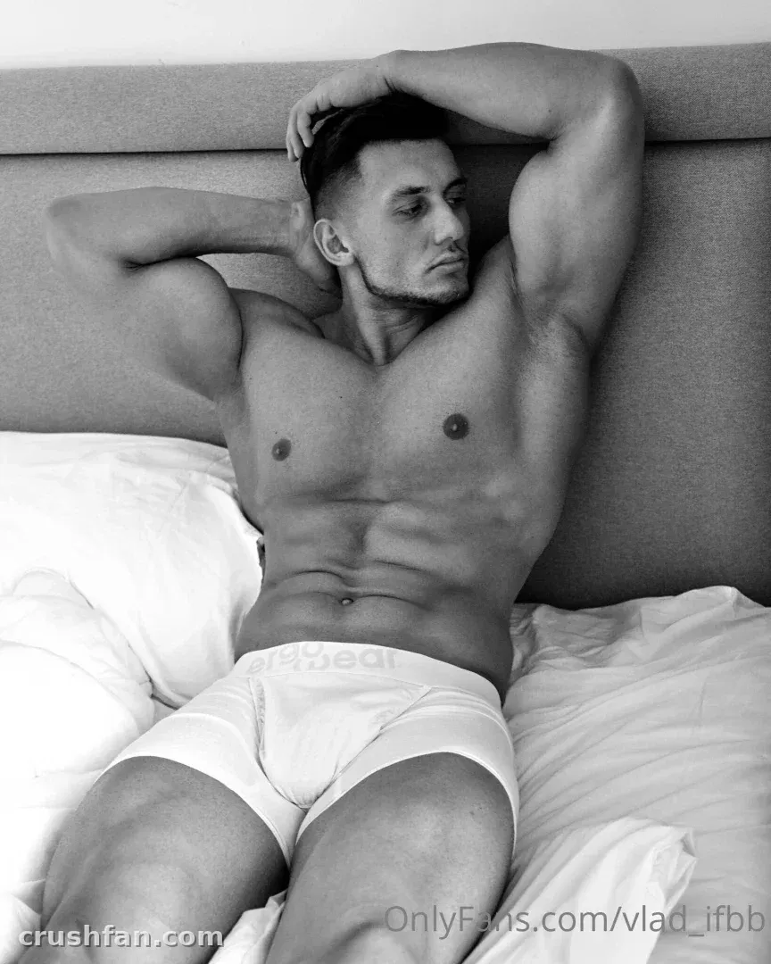 Foto em preto e branco de um homem reclinado em uma cama com um braço levantado