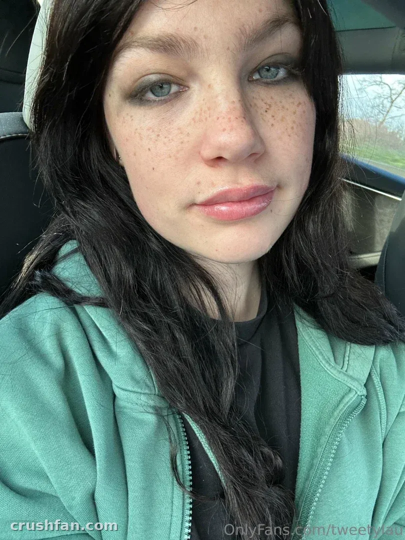 Laura com um moletom verde-menta tirando uma selfie em close-up dentro de um carro