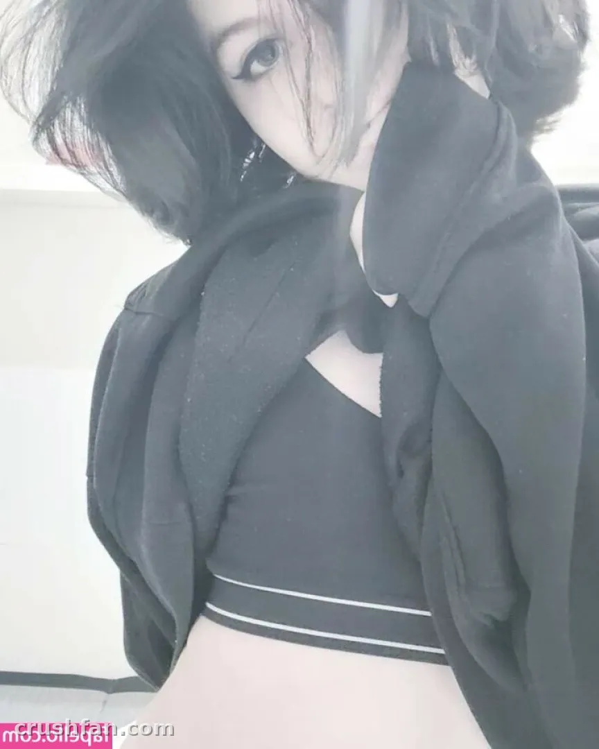 Avam wearing a black crop top and open black jacket against a light wall