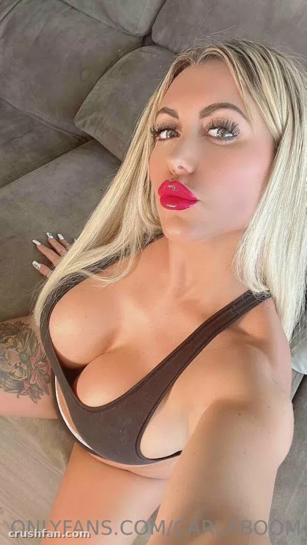 Carla Boom tomándose una selfie en un sofá gris con un top gris oscuro