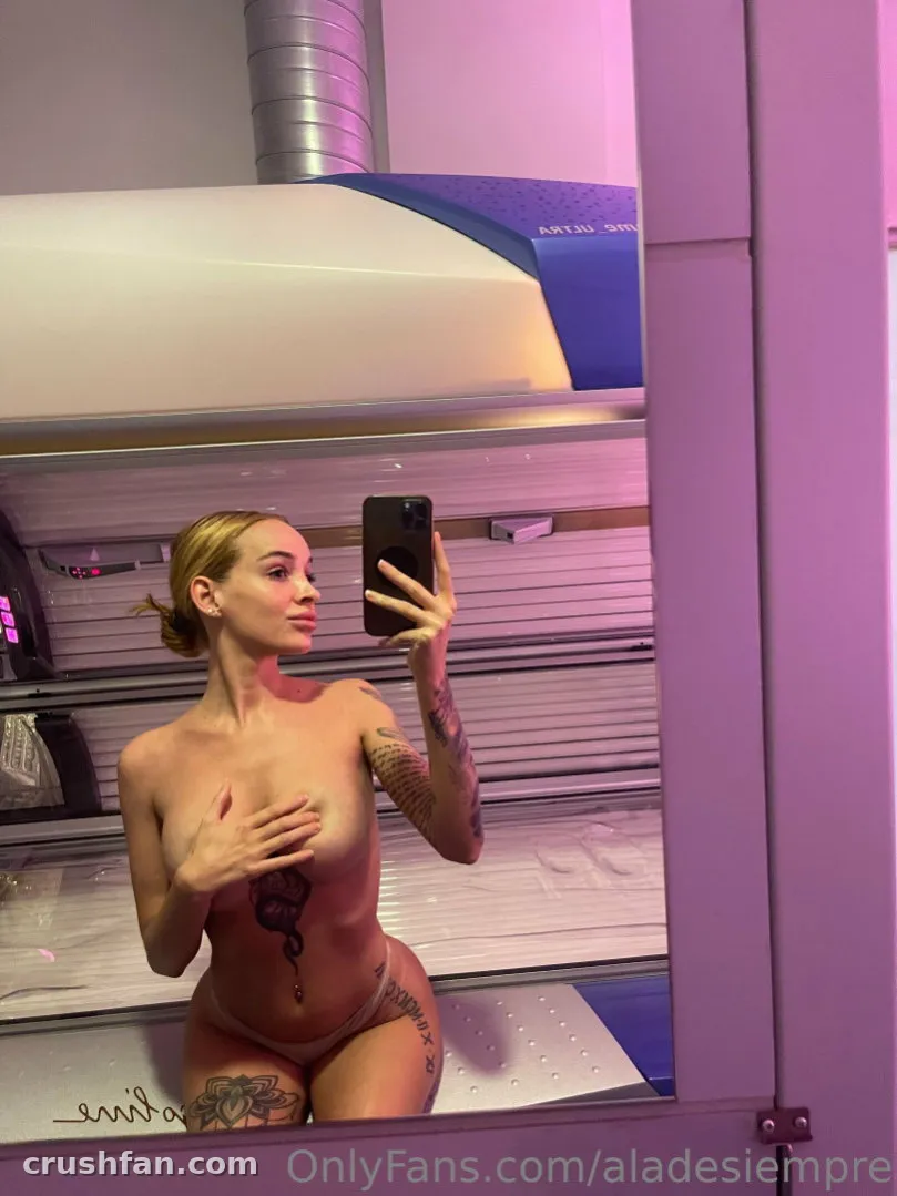 Anita macht ein Spiegel-Selfie in einem Solarium unter violettem Licht