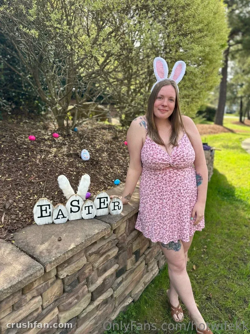 Creator in a pink floral dress and bunny ears standing by a stone wall with Easter decorations