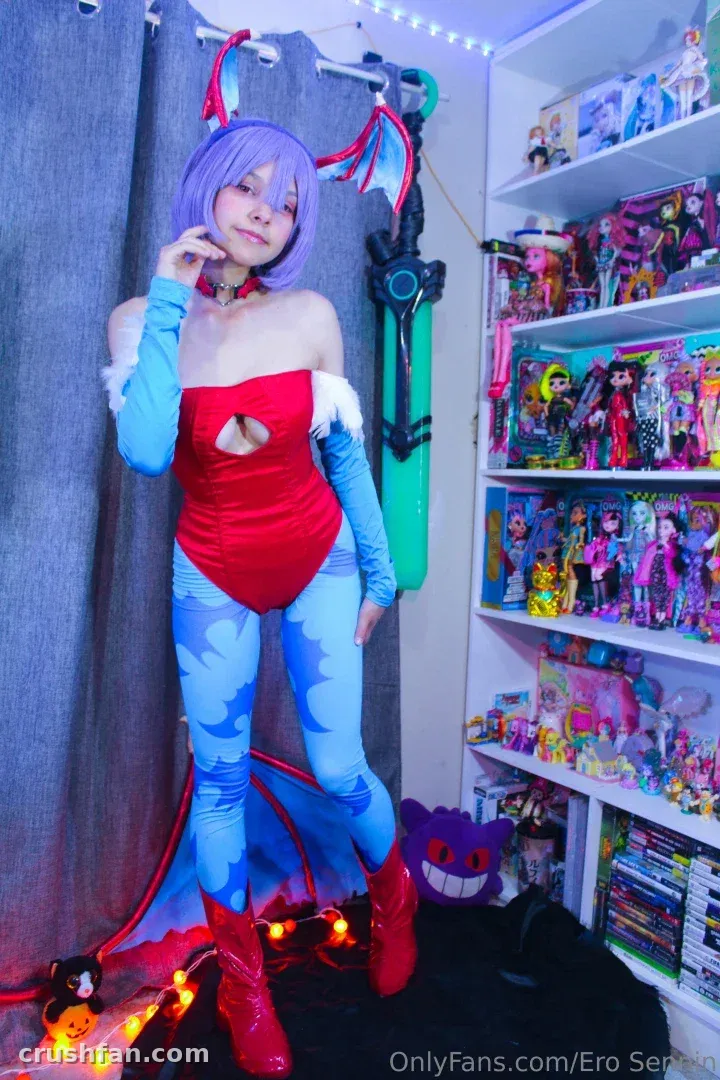 Cosplayeuse en body rouge et perruque bleue posant à l'intérieur près d'étagères de figurines.