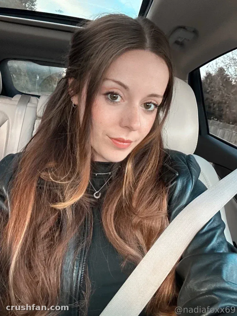 Nadia Foxx taking a selfie in a car wearing a black leather jacket.