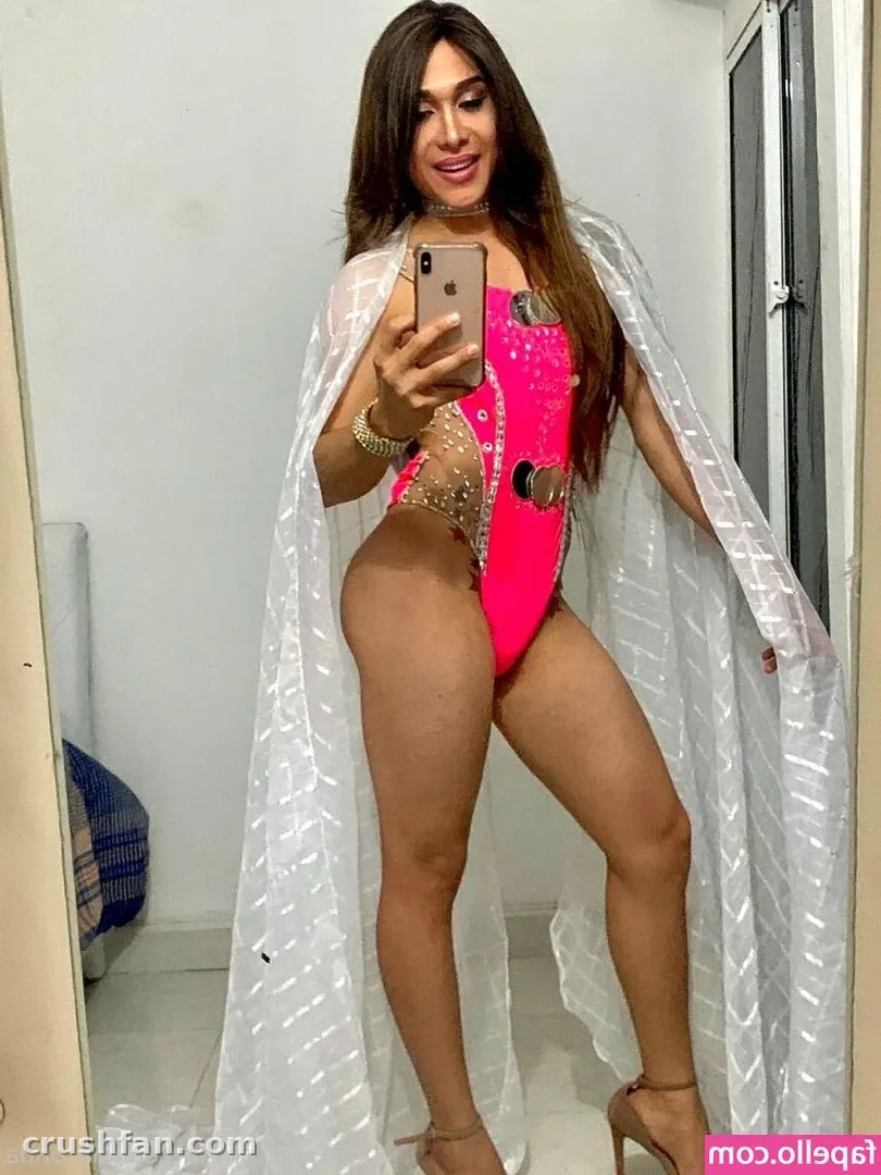 Anaconda en maillot de bain rose et châle blanc transparent prenant un selfie dans le miroir