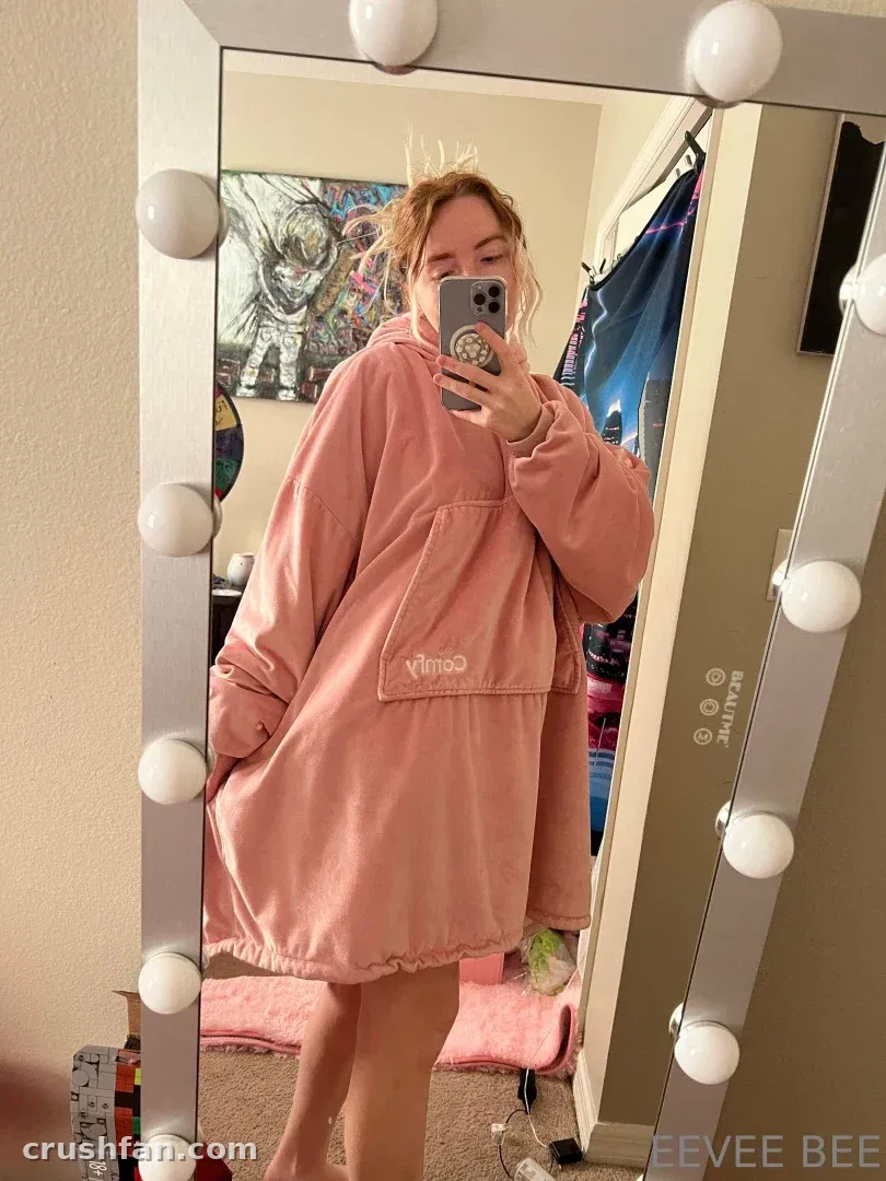 Ginger & Eevee dans une couverture à capuche rose prenant un selfie miroir dans une chambre.