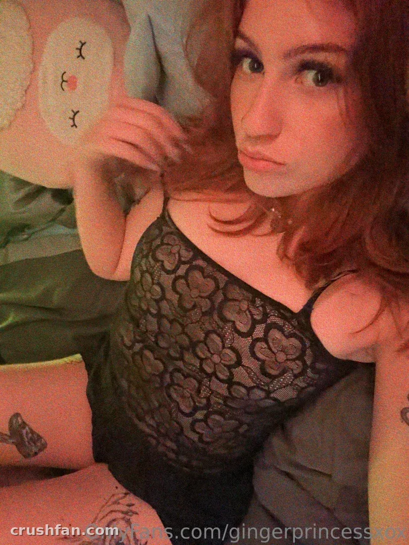 gingerprincessxox dans un haut en dentelle noire sur une literie verte, regardant vers l'appareil photo