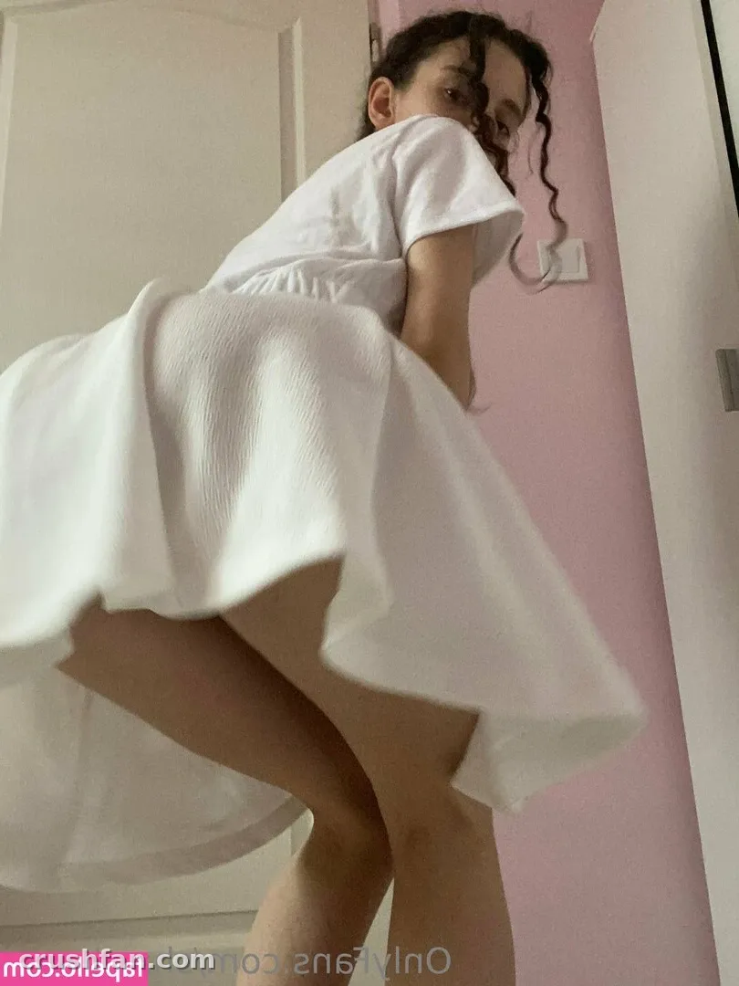 Nestix in einem weißen Kleid, das in einem Raum mit rosa Wänden zurückblickt